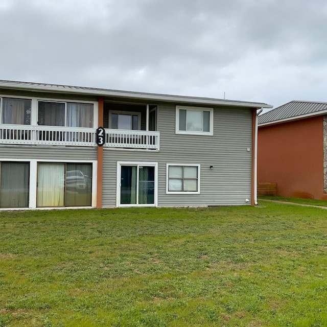 rear view of property with a balcony and a lawn