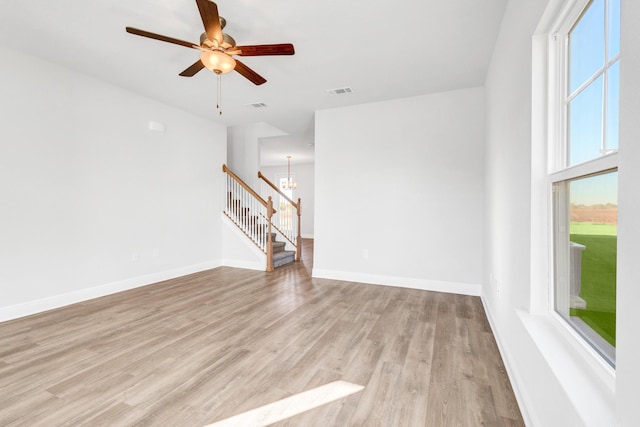 unfurnished living room featuring light hardwood / wood-style floors and ceiling fan with notable chandelier