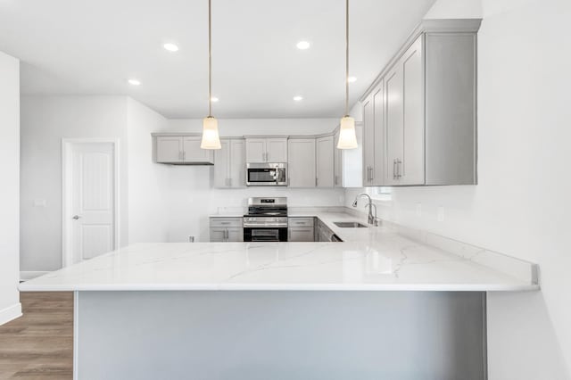 kitchen with kitchen peninsula, appliances with stainless steel finishes, decorative light fixtures, and gray cabinetry