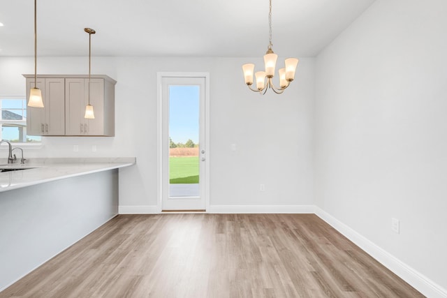 unfurnished dining area with a chandelier, light wood-type flooring, and sink