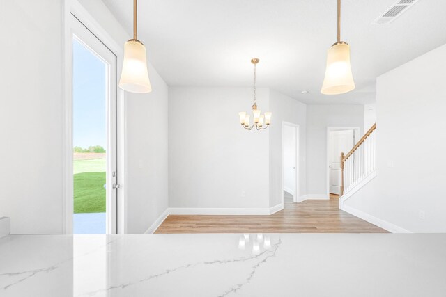 unfurnished room featuring light wood-type flooring and an inviting chandelier