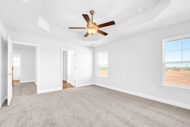 carpeted empty room featuring ceiling fan and a raised ceiling