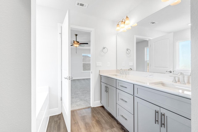 bathroom featuring vanity, a bath, ceiling fan with notable chandelier, and hardwood / wood-style flooring