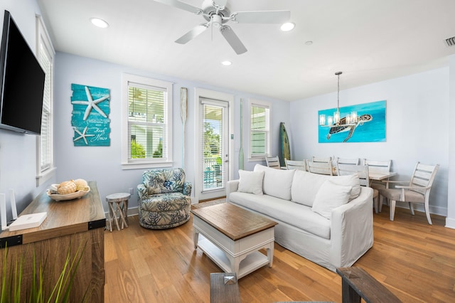 living room with ceiling fan with notable chandelier and hardwood / wood-style flooring