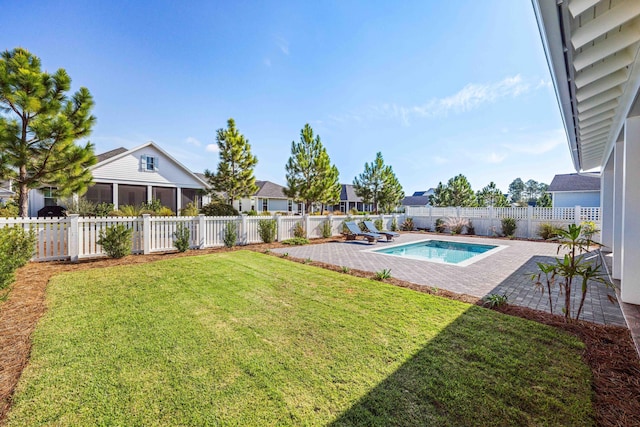 view of yard featuring a sunroom, a patio area, and a fenced in pool