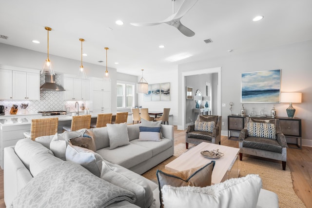 living room featuring ceiling fan, sink, and light hardwood / wood-style flooring