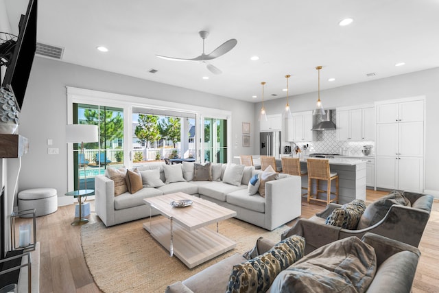 living room with ceiling fan and light hardwood / wood-style flooring