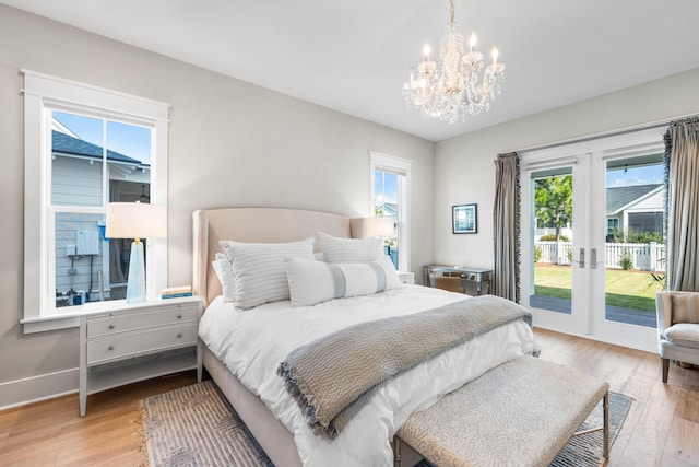 bedroom with access to outside, french doors, a notable chandelier, and light wood-type flooring