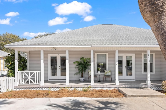 rear view of property with french doors, roof with shingles, and a porch