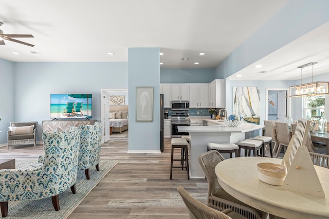 dining room with recessed lighting, light wood-style flooring, baseboards, and ceiling fan with notable chandelier