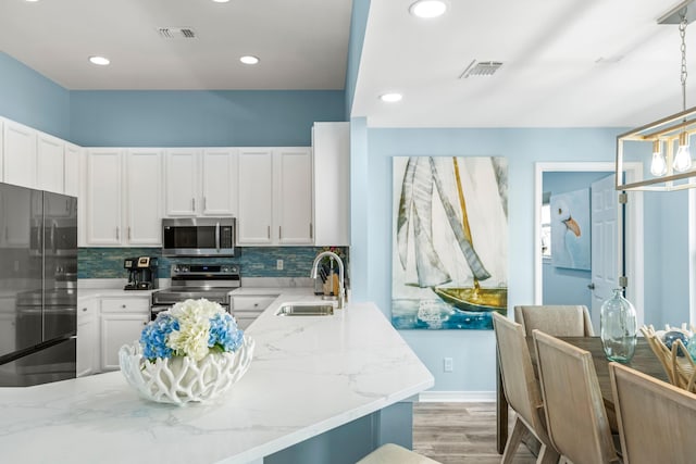 kitchen featuring stainless steel appliances, visible vents, a sink, and backsplash