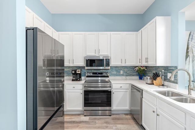 kitchen featuring appliances with stainless steel finishes, light countertops, a sink, and decorative backsplash