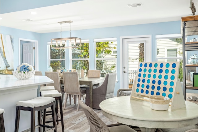 dining area with light wood-style floors, visible vents, and an inviting chandelier