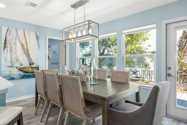 dining space featuring baseboards, light wood finished floors, visible vents, and a notable chandelier