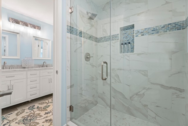 full bathroom with double vanity, a stall shower, a sink, and wood finished floors