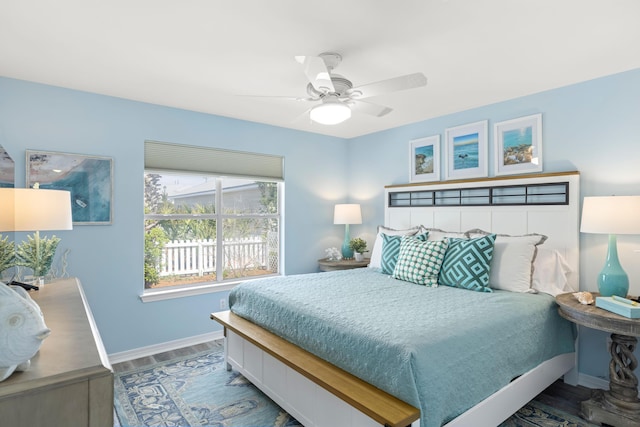 bedroom with ceiling fan, wood finished floors, and baseboards