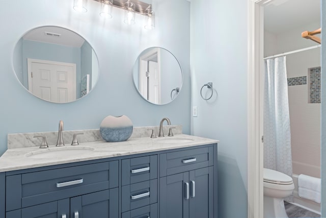 bathroom with double vanity, shower / bath combo, toilet, and a sink