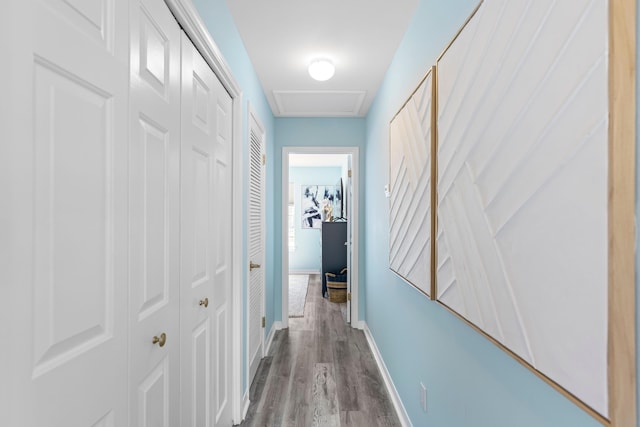 hall with attic access, baseboards, and wood finished floors