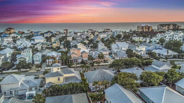 aerial view at dusk featuring a residential view and a water view