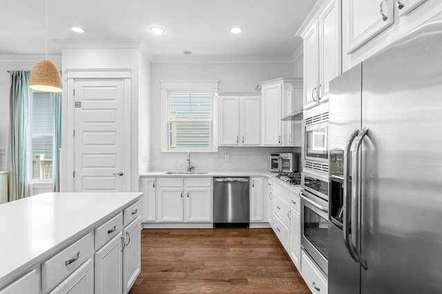 kitchen featuring appliances with stainless steel finishes, dark wood-type flooring, white cabinetry, decorative light fixtures, and tasteful backsplash