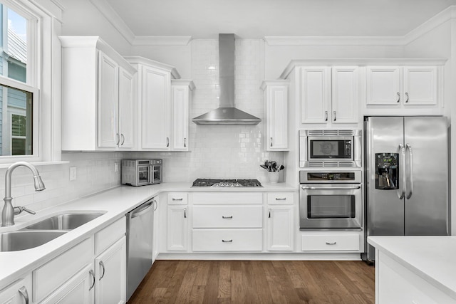 kitchen featuring sink, wall chimney exhaust hood, white cabinetry, and appliances with stainless steel finishes