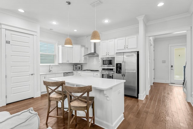 kitchen featuring a center island, decorative light fixtures, stainless steel appliances, backsplash, and white cabinetry