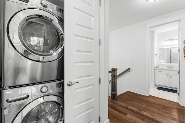 laundry area with stacked washing maching and dryer, dark hardwood / wood-style flooring, and sink