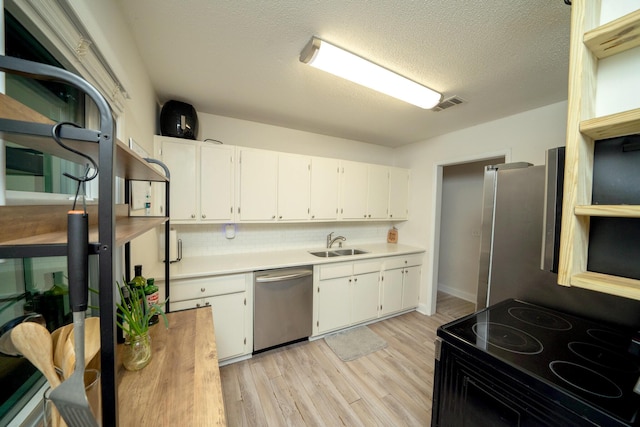 kitchen with appliances with stainless steel finishes, sink, light hardwood / wood-style flooring, and white cabinets