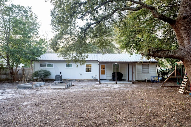 rear view of house featuring a playground and central air condition unit