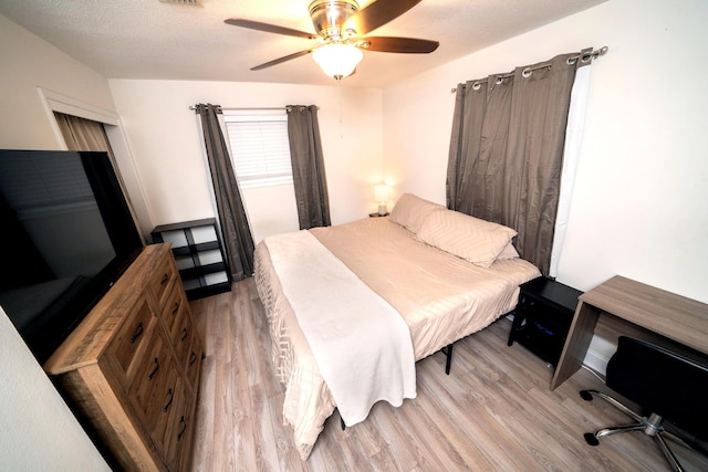 bedroom with ceiling fan, a textured ceiling, and light hardwood / wood-style floors