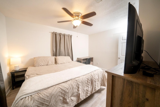 bedroom with hardwood / wood-style flooring, a textured ceiling, and ceiling fan