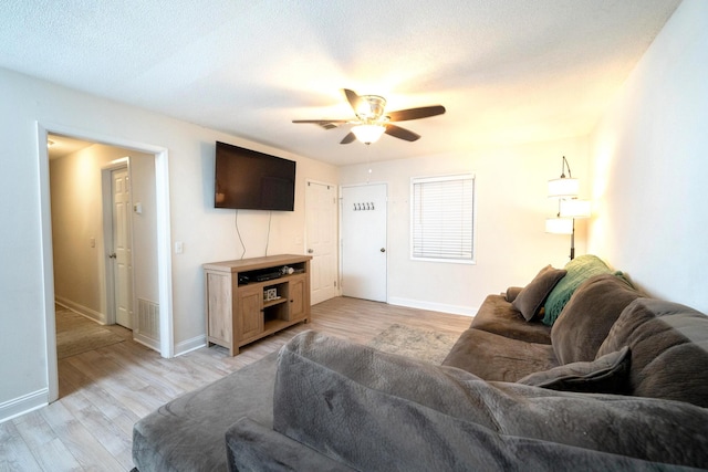 living room with a textured ceiling, light hardwood / wood-style floors, and ceiling fan