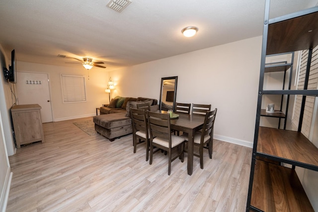 dining space with ceiling fan and light wood-type flooring