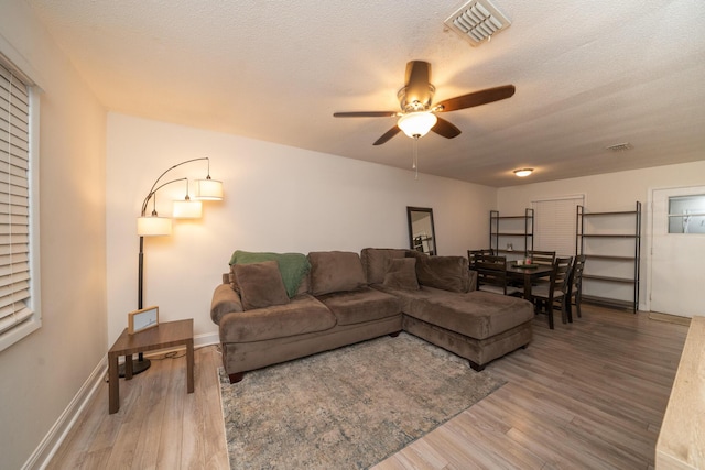 living room featuring ceiling fan, wood-type flooring, and a textured ceiling