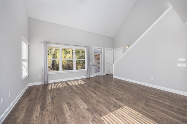 unfurnished living room with high vaulted ceiling and dark wood-type flooring