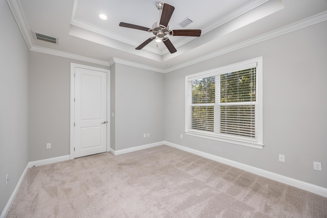 empty room featuring a tray ceiling, crown molding, ceiling fan, and light colored carpet