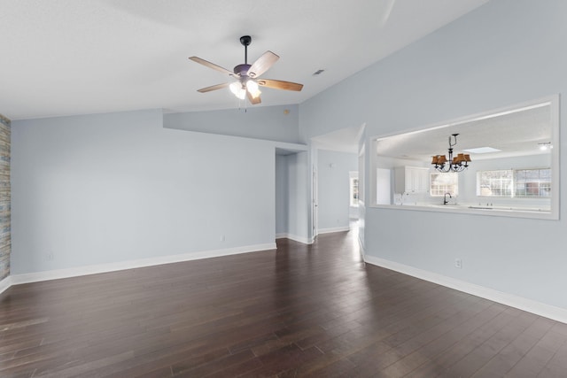 empty room with ceiling fan with notable chandelier, lofted ceiling, and dark wood-type flooring