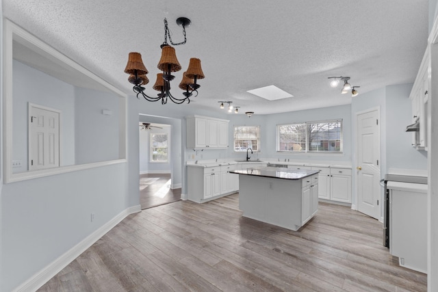 kitchen with white cabinetry, a kitchen island, light hardwood / wood-style floors, and sink