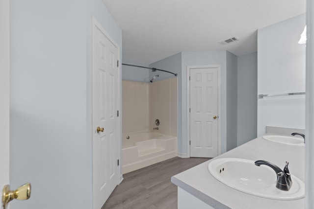 bathroom featuring vanity, shower / bathtub combination, wood-type flooring, and a textured ceiling