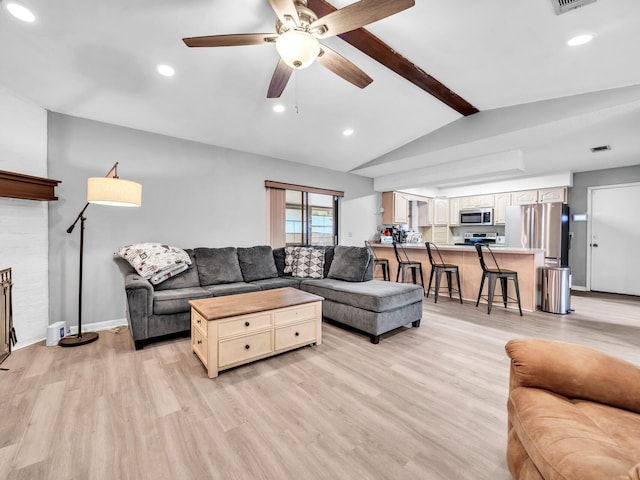 living room with ceiling fan, lofted ceiling with beams, and light wood-type flooring