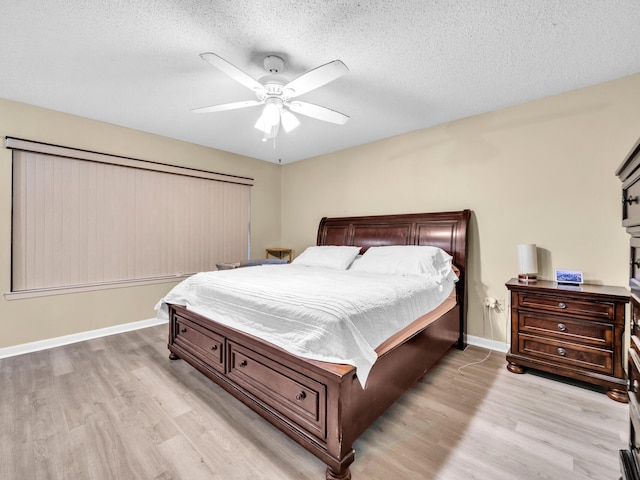 bedroom with ceiling fan, light hardwood / wood-style floors, and a textured ceiling