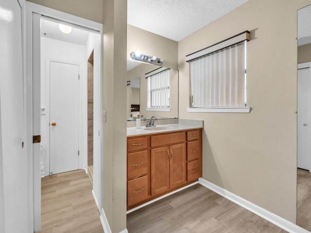 bathroom with a textured ceiling, wood-type flooring, and vanity