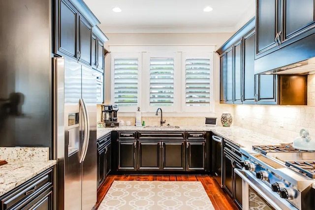 kitchen with light stone countertops, appliances with stainless steel finishes, dark brown cabinets, dark wood-type flooring, and sink