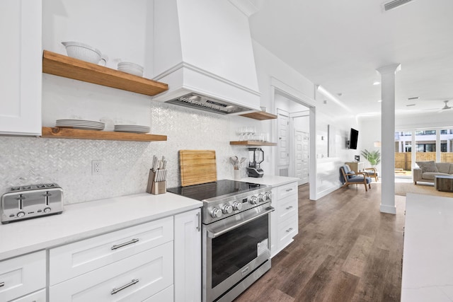 kitchen with premium range hood, stainless steel stove, decorative backsplash, white cabinetry, and decorative columns