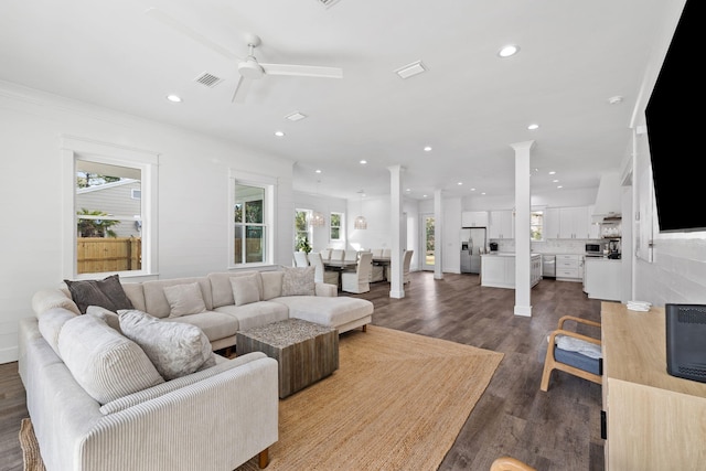 living room featuring decorative columns, ceiling fan, crown molding, and dark hardwood / wood-style floors