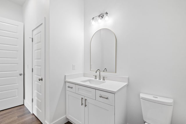 bathroom with hardwood / wood-style flooring, vanity, and toilet