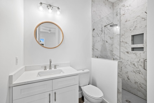 bathroom with tiled shower, vanity, and toilet