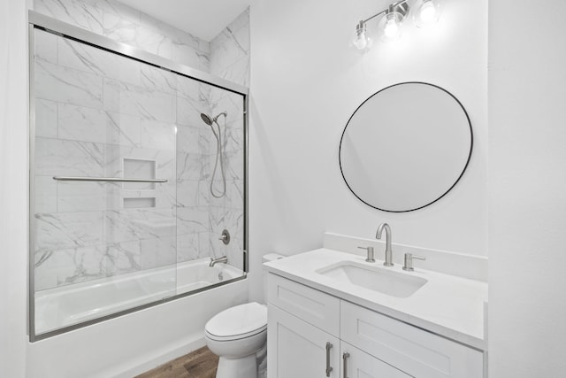 full bathroom with shower / bath combination with glass door, hardwood / wood-style floors, vanity, and toilet