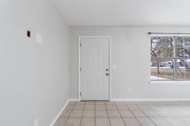 interior space with a healthy amount of sunlight, light tile patterned floors, and a textured ceiling