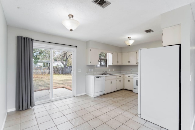 kitchen featuring white cabinetry, sink, light tile patterned floors, white appliances, and a textured ceiling